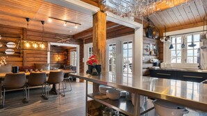 Un intérieur rustique avec des murs en bois, un coin repas, un comptoir de cuisine et des verres à vin suspendus.