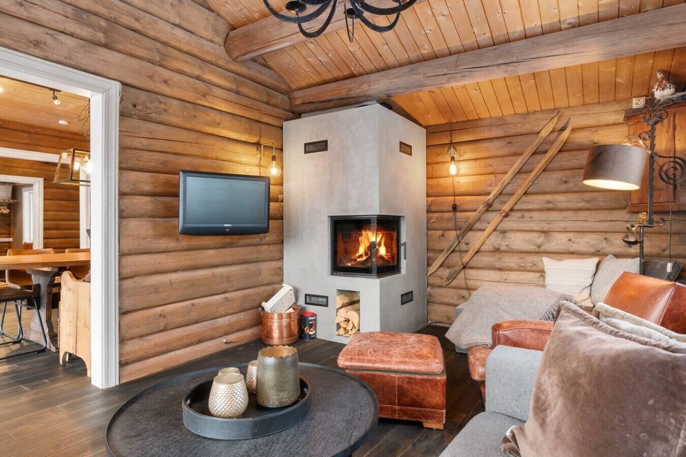 En stuga byggd av timmer med en öppen spis, en tv, en matplats och en mysig sittgrupp.