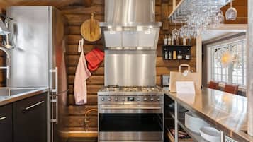 A modern kitchen with stainless steel appliances, wooden walls, and a dining area with a view.