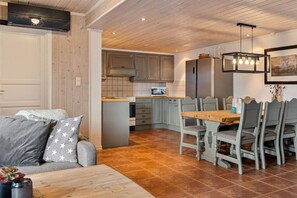Un espacio de sala cómodo con un sofá, una mesa de comedor con sillas y una cocina con armarios y electrodomésticos.