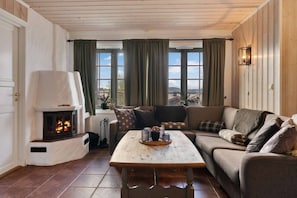 A cozy living room with a fireplace, a sofa, a coffee table, and a view of a bridge.