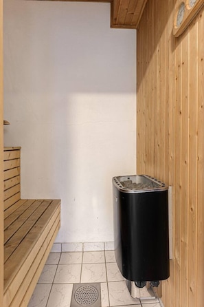 A sauna room with a wooden bench, a black sauna heater, and a tiled floor. - TH752 Ski-In/Out Apartment, prefect location, Sauna (Trysil)