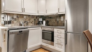 A modern kitchen with white cabinets, stainless steel appliances, and a tiled backsplash. - Trysil Ski-in/out, Sauna, Groups (Trysil)