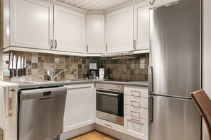 A modern kitchen with white cabinets, stainless steel appliances, and a tiled backsplash. - Trysil Ski-in/out, Sauna, Groups (Trysil)