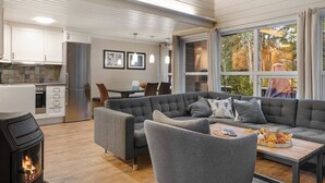 A modern living room with a sectional sofa, a fireplace, and a dining area with a table and chairs. - Trysil Ski-in/out, Sauna, Groups (Trysil)