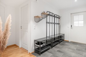 A hallway with a black metal bench, a wall-mounted coat rack, and a door. - GO11 Trysil Ski-in out Apt, Private Sauna, Sleeps 9 (Trysil)