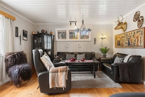 A cozy living room with a leather sofa, a black armchair, and a wooden floor. - Trysil Ski-in/out Cabin w/ Fireplace (Trysil)