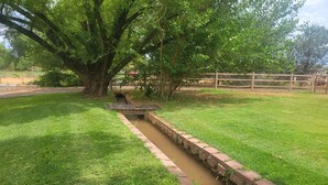 Une zone herbeuse avec un étroit canal d’eau et une clôture en bois.