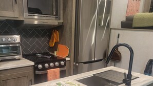 Une cuisine moderne dotée d’un îlot central intégré, d’appareils électroménagers en acier inoxydable et d’un pare-feu.