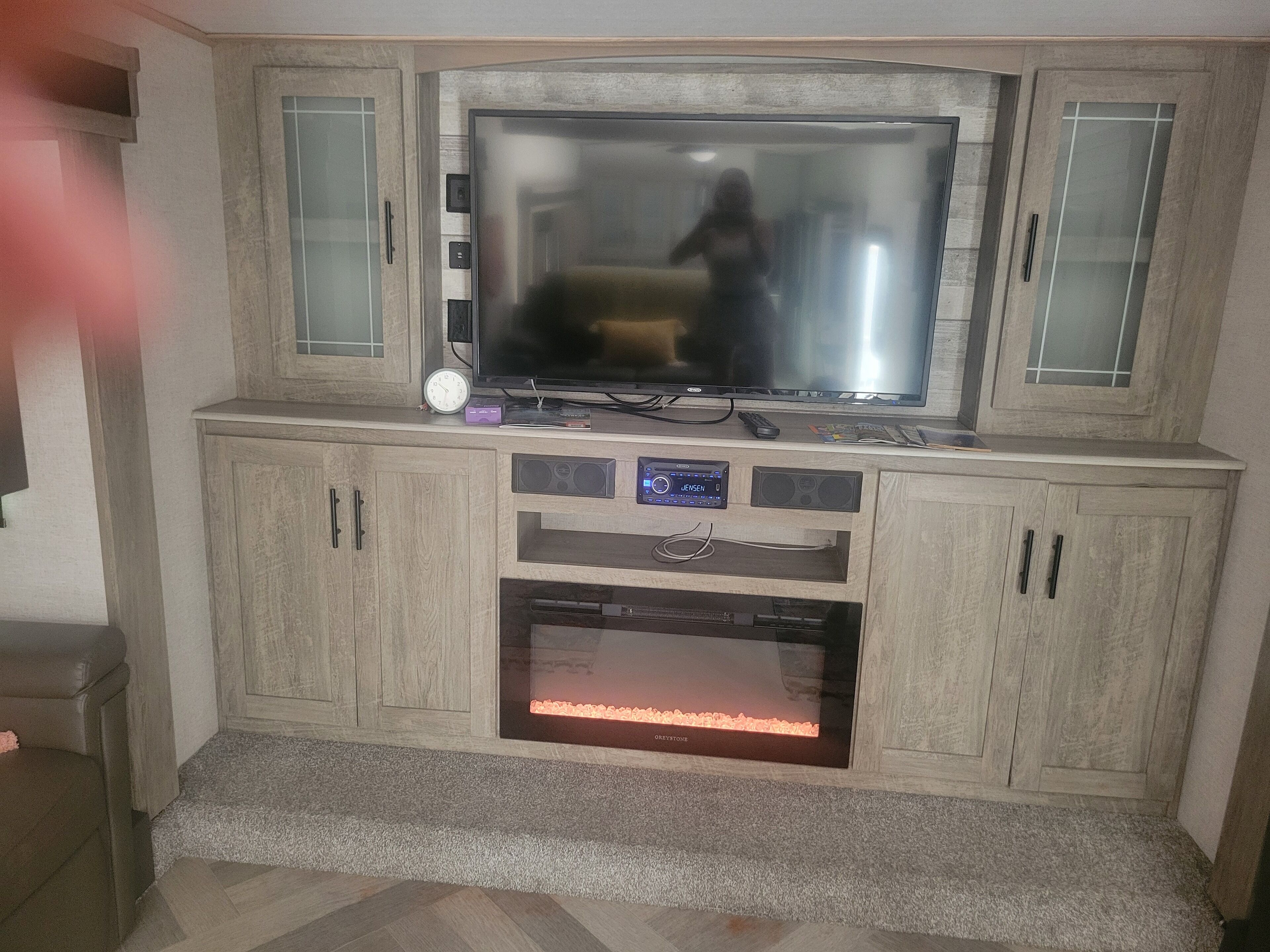 A living room with a large flat-screen TV, built-in speakers, and a fireplace.