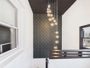 A modern kitchen with a unique backsplash, a hanging light fixture, and a window with blinds.