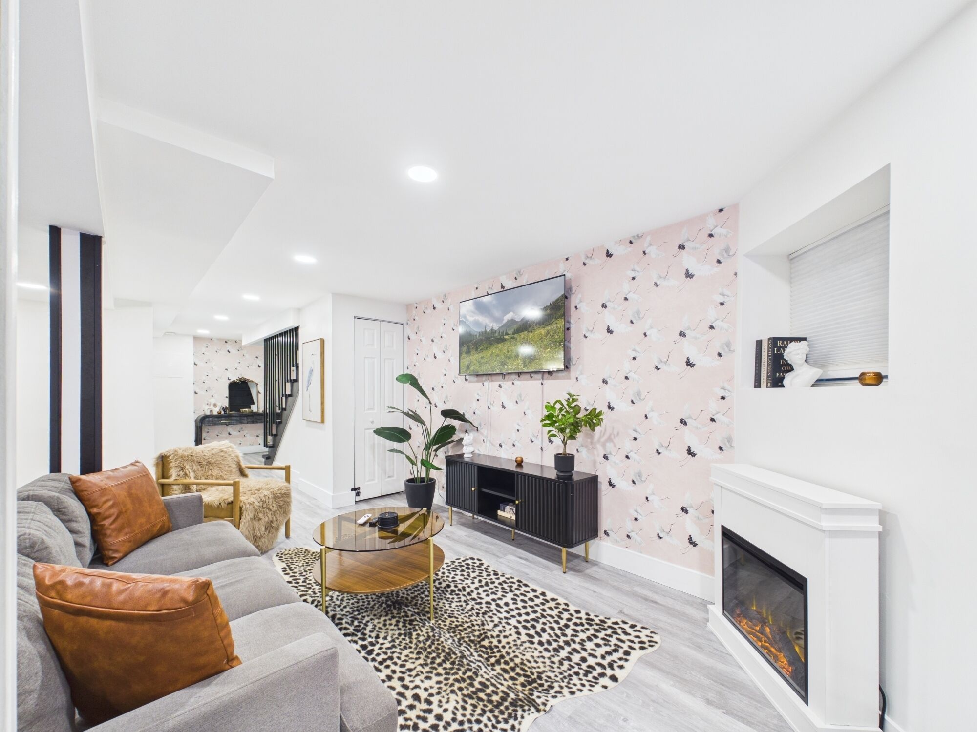 Una sala de estar moderna con un sofá, una mesa de centro, una chimenea y un televisor montado en la pared.