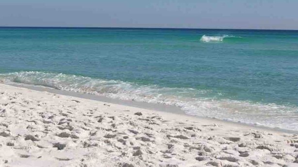 Ein Strand mit weißem Sand und klarem, blauem Wasser.