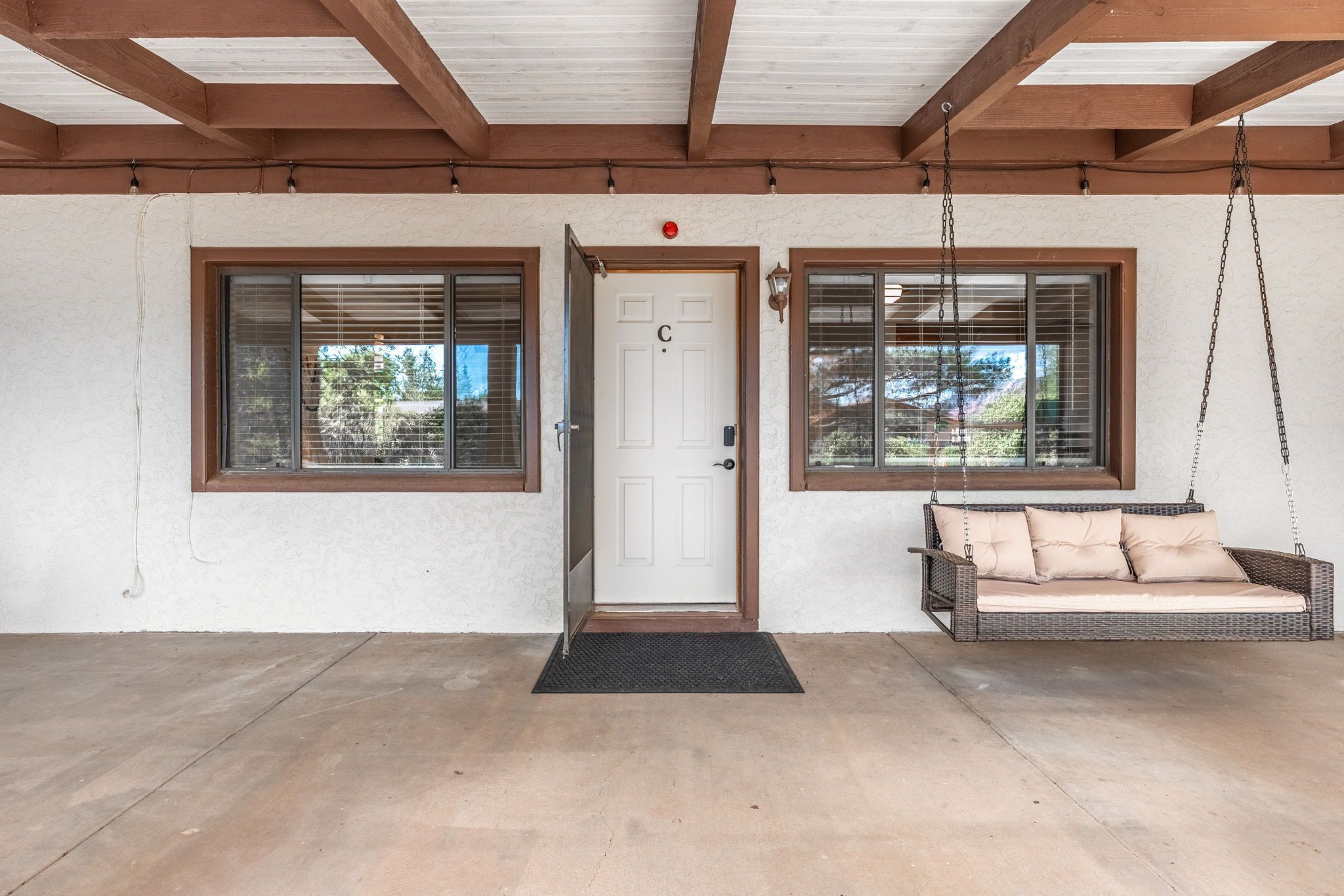 A covered porch with a door, two windows, and a swing chair.