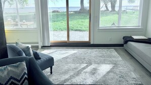 A living room with a large sliding glass door to a patio, a sofa, and a patterned rug.