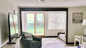 A modern living room with a grey sofa, a white coffee table, and a large window with a view of the outdoors.