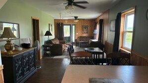 A spacious living area with a dining table, sofas, and a kitchen area with wooden cabinets and a countertop. - Back to the Old Farm (Ashland)