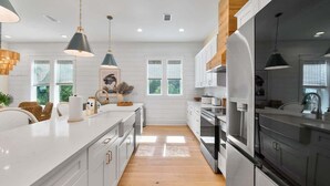 A modern kitchen with white cabinetry, wooden flooring, and pendant lighting. - Barefoot on 30a by Stay on 30a (Seacrest Beach)