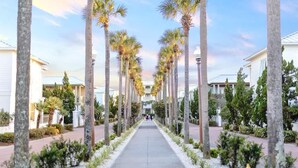 A pathway lined with palm trees and buildings, suggesting a resort or hotel setting. - Barefoot on 30a by Stay on 30a (Seacrest Beach)