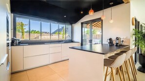 Une cuisine moderne dotée d’un grand îlot central, de tabourets de bar et offrant une vue sur l’extérieur.