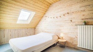 Ett litet, ombonat rum med ett sluttande tak, en enkel säng, ett litet bord med en lampa och ett element.