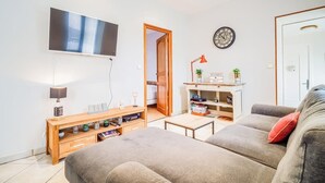 Ett modernt vardagsrum med en platt-TV, ett bord i trä, en grå soffa och ett litet soffbord.