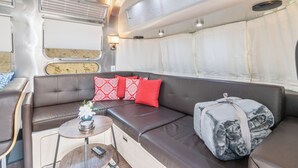 Een gezellig interieur met een leren bank, een tafeltje met een vaas en een plaid op de vloer.