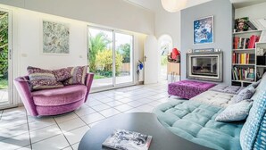 Un salon moderne avec un canapé violet, un canapé turquoise, une table basse et une bibliothèque.