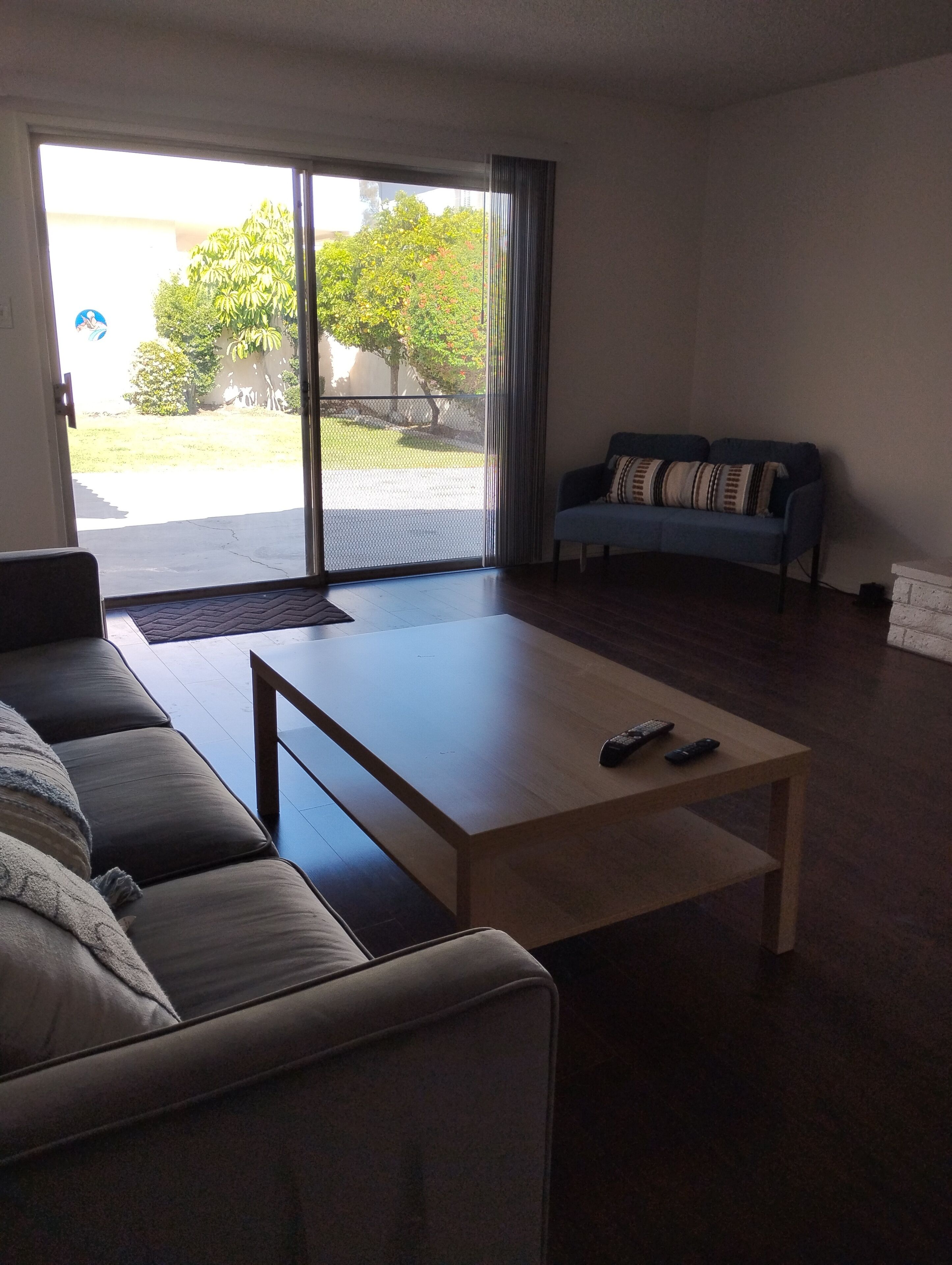 A living room with a sofa, a coffee table, and a sliding glass door leading to a balcony.
