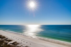 Uma praia com céu limpo, sol radiante e águas calmas do oceano.