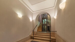 A staircase with a wooden handrail and a dark rug at the bottom.