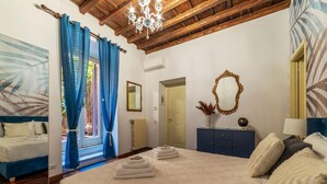 A bedroom with a bed, a dresser, a mirror, and a chandelier. - One Bedroom Apartment (ROMA)