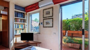 A hotel room with a large window, a bookshelf, a flat-screen TV, and a bed with towels. - One Bedroom Apartment (ROMA)