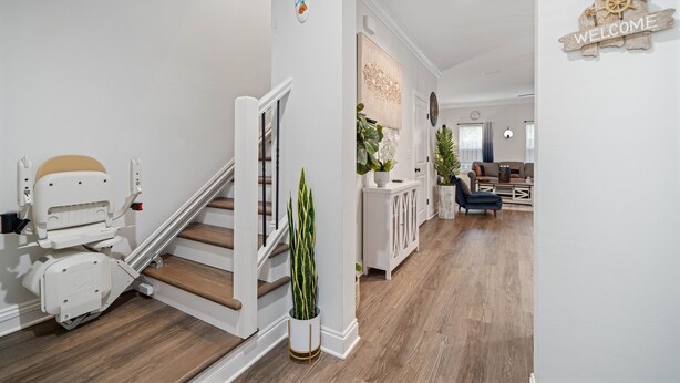 Un intérieur moderne avec un escalier en bois, une console blanche et une pancarte indiquant « BIENVENUE ».
