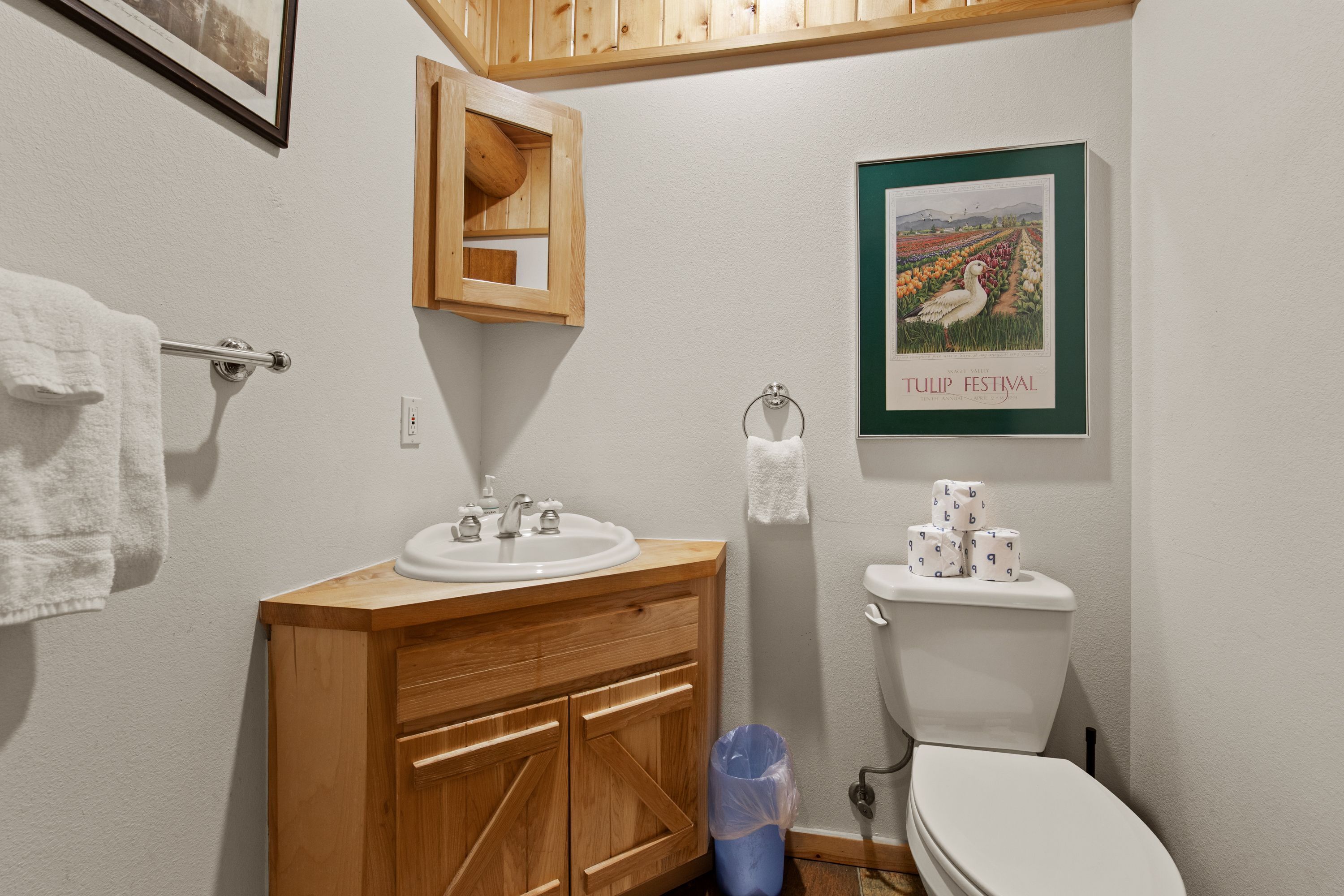 A bathroom with a wooden vanity, a white sink, and a toilet.