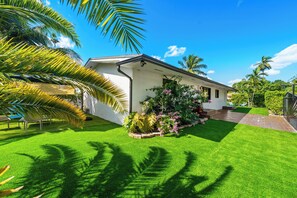 A house with a well-maintained lawn, a porch with plants, and a clear blue sky. - Casa Verde - 5 BDRM / 2 BA with POOL + HOT TUB (Miami)