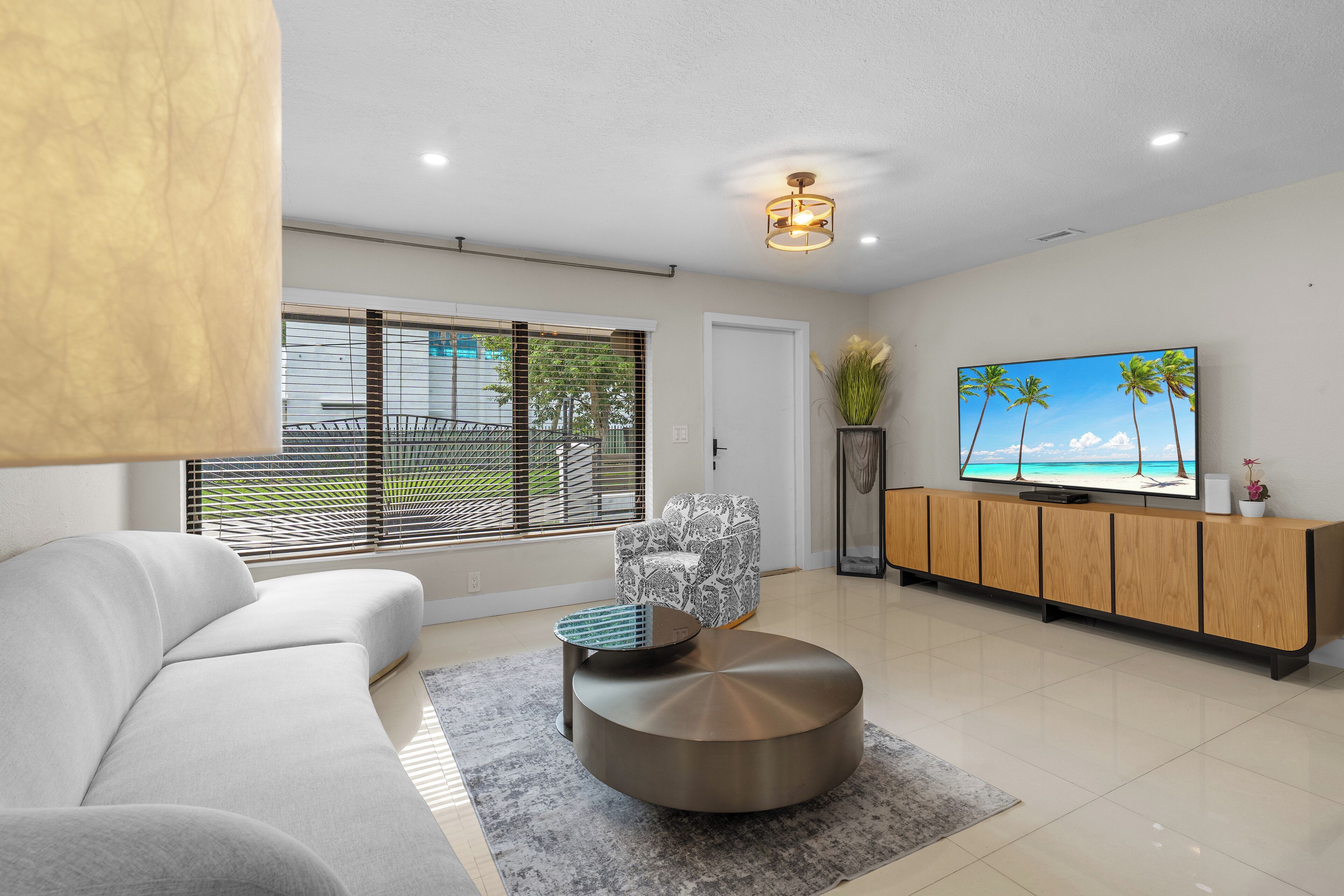 A modern living room with a sofa, a round coffee table, a television, and a cabinet.