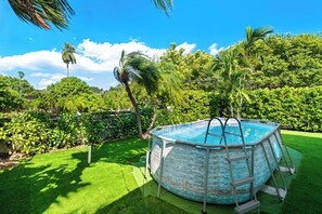 A round above-ground pool with a ladder, surrounded by lush greenery and palm trees. - Casa Verde - 5 BDRM / 2 BA with POOL + HOT TUB (Miami)