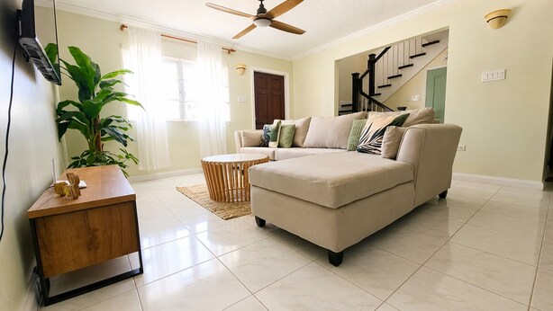 A living room with a sofa, a coffee table, a TV, and a plant. - NEW! Hilltop Escape with Ocean Views (Montego Bay)