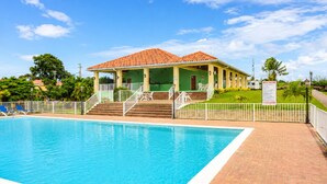 A poolside building with a tiled roof, a covered patio, and a signboard. - NEW! Hilltop Escape with Ocean Views (Montego Bay)