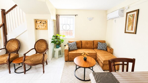 Una sala de estar con un sofá, dos sillones, una mesa de centro y una mesa de comedor.
