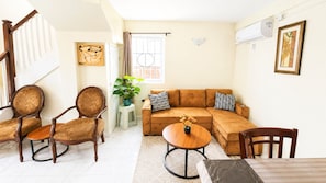 A living room with a sofa, two armchairs, a coffee table, and a dining table.