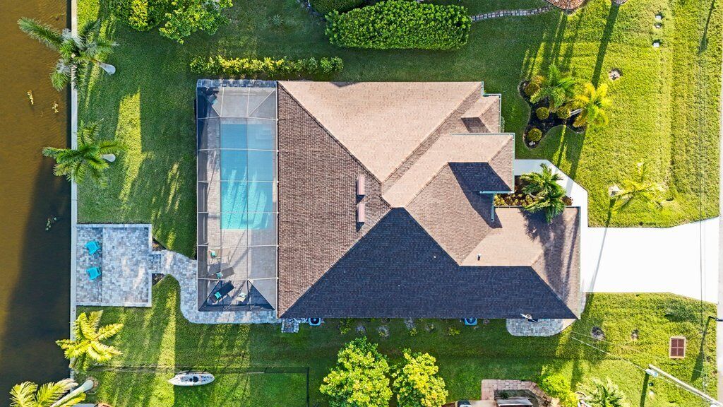 Oversigtsbillede af et hus med swimmingpool, overdækket terrasse og anlagt græsplæne.
