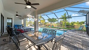 Une terrasse extérieure avec une table à plateau de verre, des chaises et une piscine.