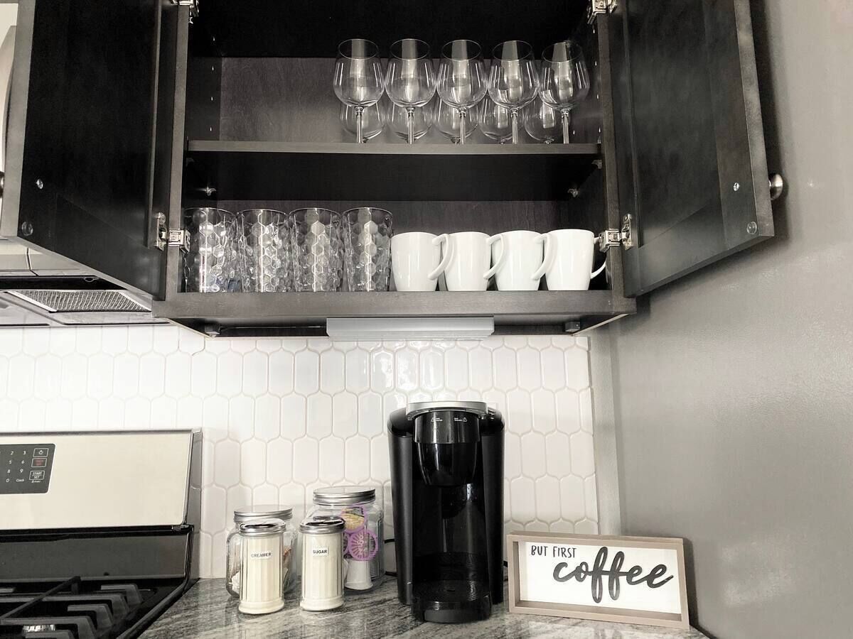 Eine Küche mit Kaffeemaschine, Zucker- und Sahnedosen, und einem Schild mit dem Schriftzug 'Zuerst Kaffee'.