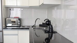 A modern kitchen with white cabinets, a black countertop, and a stainless steel range hood. - Apartment near the airport, The Greey's house D (El Calero)