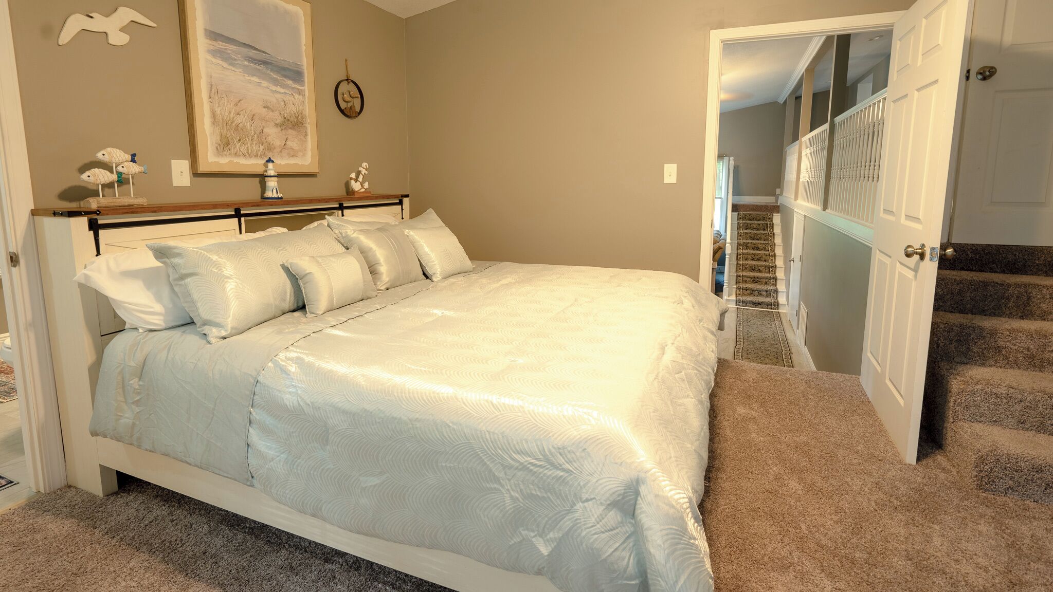 Ein Schlafzimmer mit einem großen Bett, einem Nachttisch, einem Gemälde und einer Treppe, die in eine obere Ebene führt.