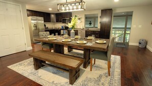 Una cocina moderna con armarios de madera oscura, un refrigerador de acero inoxidable y un comedor con una mesa de madera lista para cuatro.