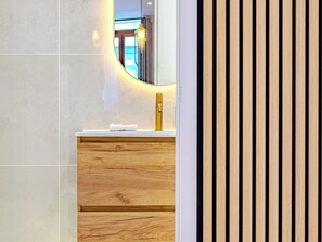 A bathroom with a wooden vanity, a gold faucet, and a mirror with a circular light. - The Theater Lodge - Parking included - City center (Béziers)