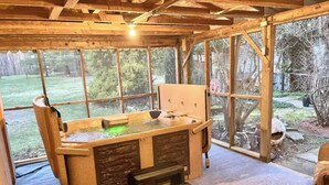 Un área de spa con hidromasaje, bancos de madera y amplios ventanales con vistas al exterior.